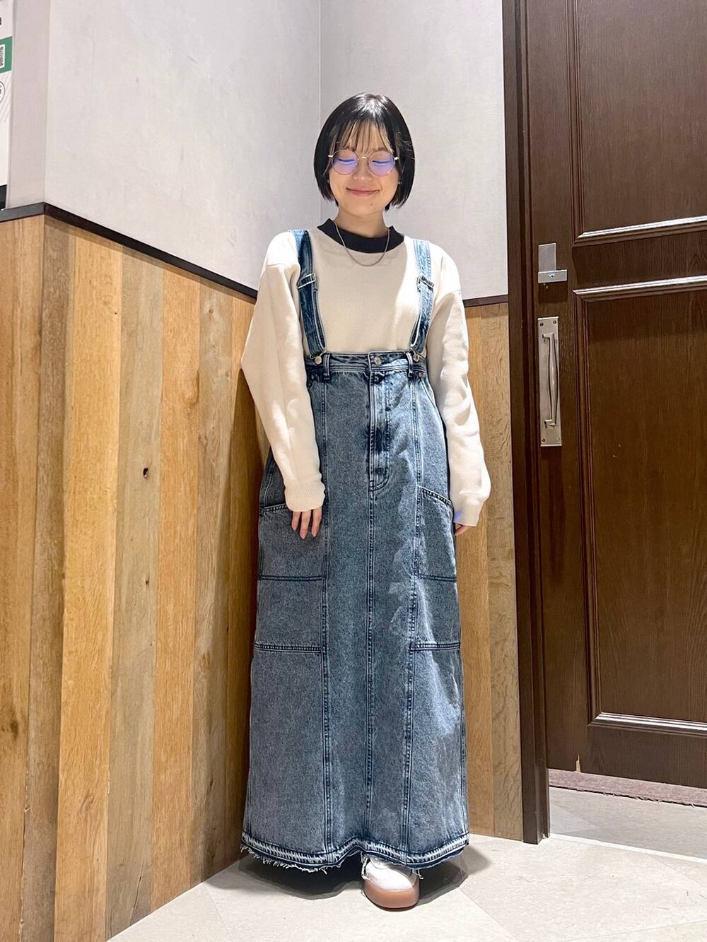 ブルー系のデニムスカート、ホワイト系のニット/セーター、ホワイト系のスニーカーを着用したレディースの秋コーディネートの5枚目の写真