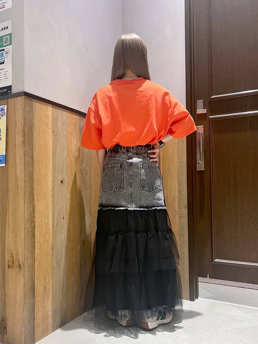 オレンジ系のTシャツ/カットソー、ホワイト系のスニーカー、ブラック系のデニムスカートを着用したレディースの夏コーディネートの3枚目の写真