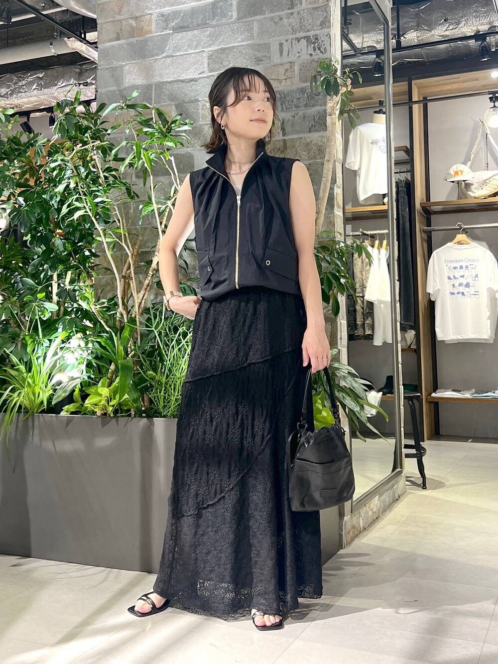 ブラック系のベスト、ホワイト系のタンクトップ、ブラック系のショルダーバッグを着用したレディースの夏コーディネートの2枚目の写真