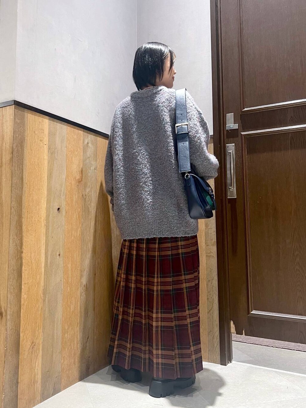 グリーン系のニット/セーター、ブラック系のブーツ、ブルー系のショルダーバッグを着用したレディースの秋コーディネートの3枚目の写真