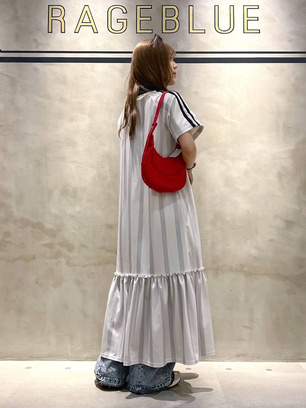 ホワイト系のワンピース、ブルー系のデニムパンツ、ホワイト系のスニーカーを着用したレディースの夏コーディネートの3枚目の写真