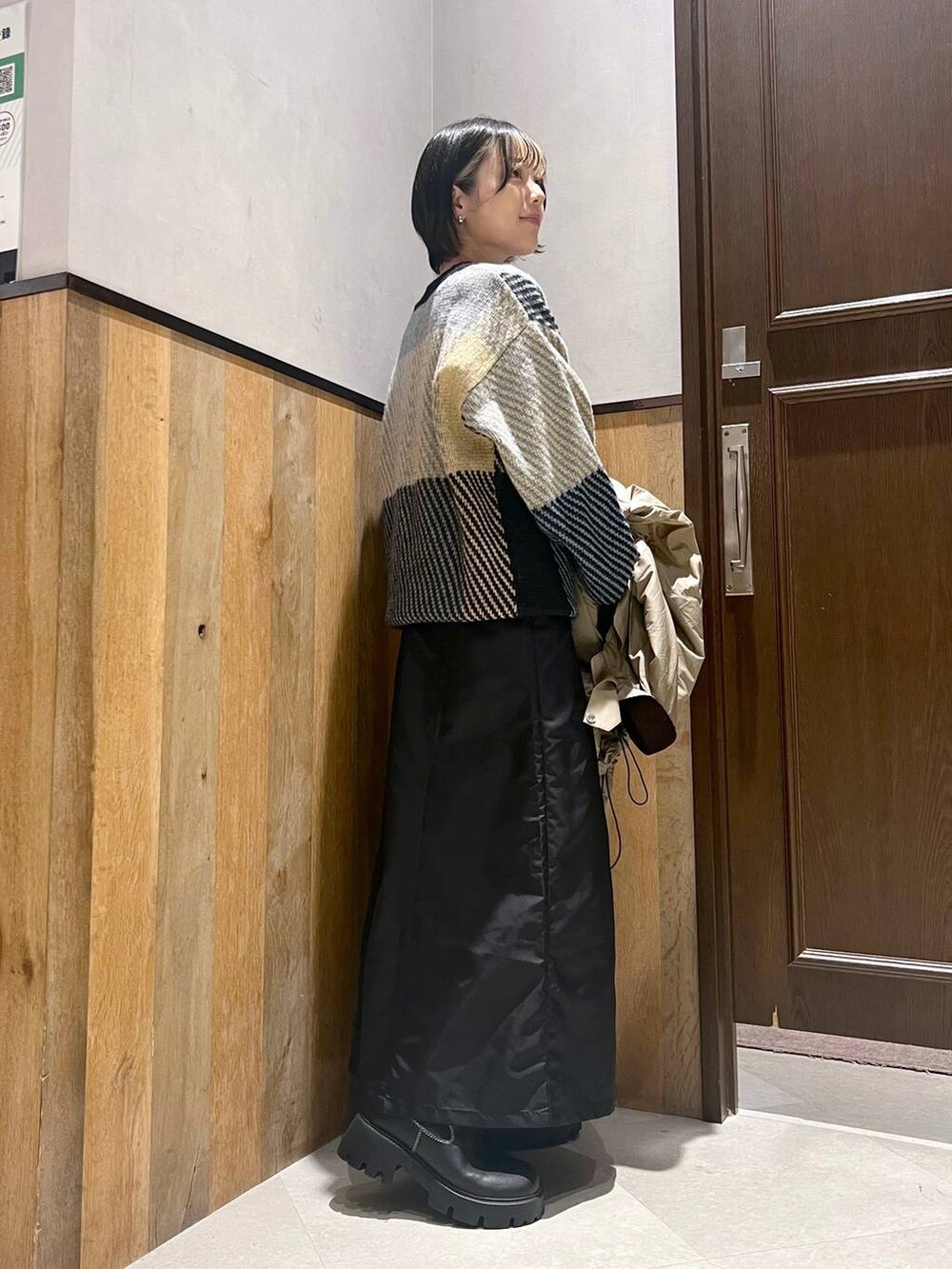 ブラック系のブーツ、ベージュ系のミリタリージャケット、ブラック系のジャンパースカートを着用したレディースの秋コーディネートの7枚目の写真