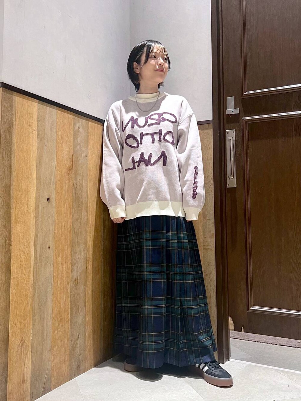 ホワイト系のニット/セーター、グリーン系のスカート、ブラック系のスニーカーを着用したレディースの秋コーディネートの2枚目の写真