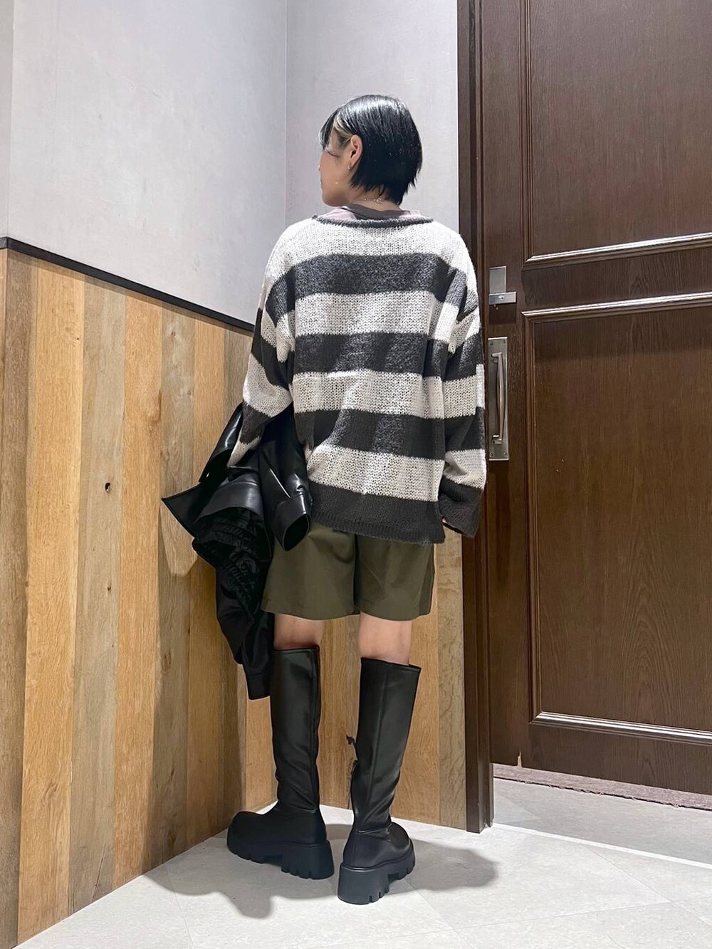ブラック系のブーツ、ホワイト系のニット/セーター、ブラック系のブルゾンを着用したレディースの秋コーディネートの3枚目の写真