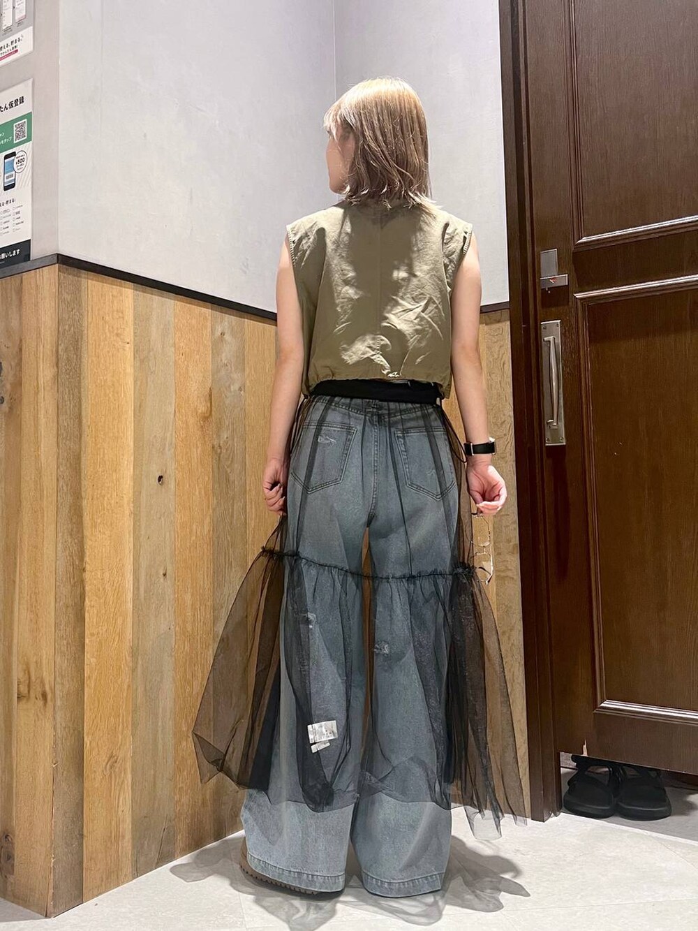 ブルー系のデニムパンツ、ブラック系のスカート、グリーン系のベストを着用したレディースの夏コーディネートの4枚目の写真