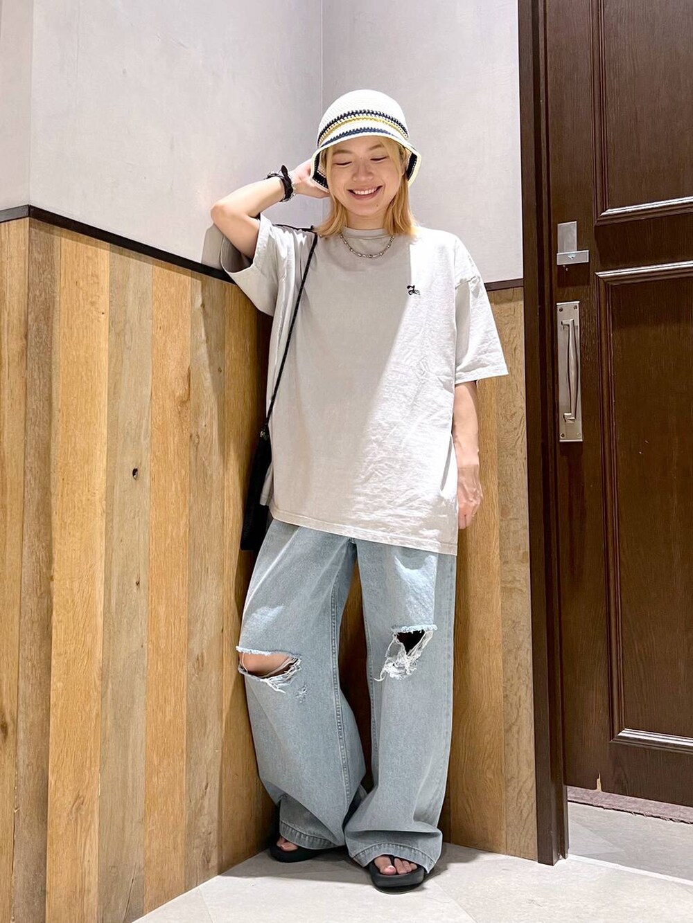 ブルー系のデニムパンツ、ブラック系のショルダーバッグ、ベージュ系のTシャツ/カットソーを着用したレディースの夏コーディネートの4枚目の写真