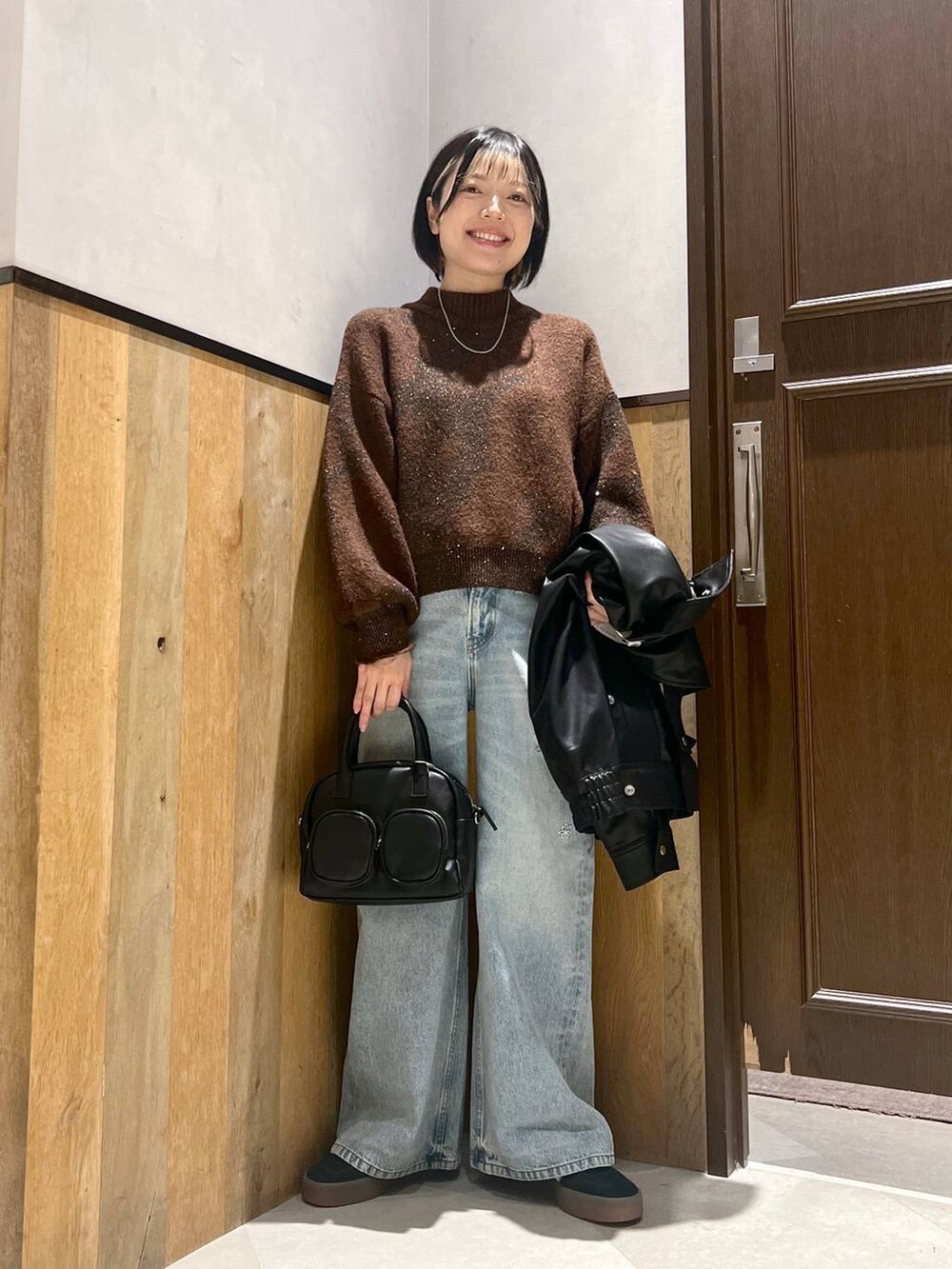 ブルー系のデニムパンツ、ブラック系のショルダーバッグ、ブラック系のブルゾンを着用したレディースの秋コーディネートの4枚目の写真