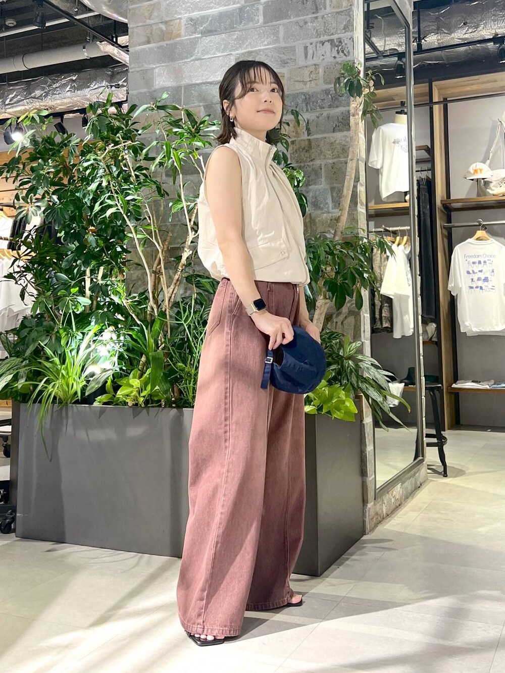 ホワイト系のベスト、ブラック系のサンダル、レッド系のデニムパンツを着用したレディースの夏コーディネートの3枚目の写真