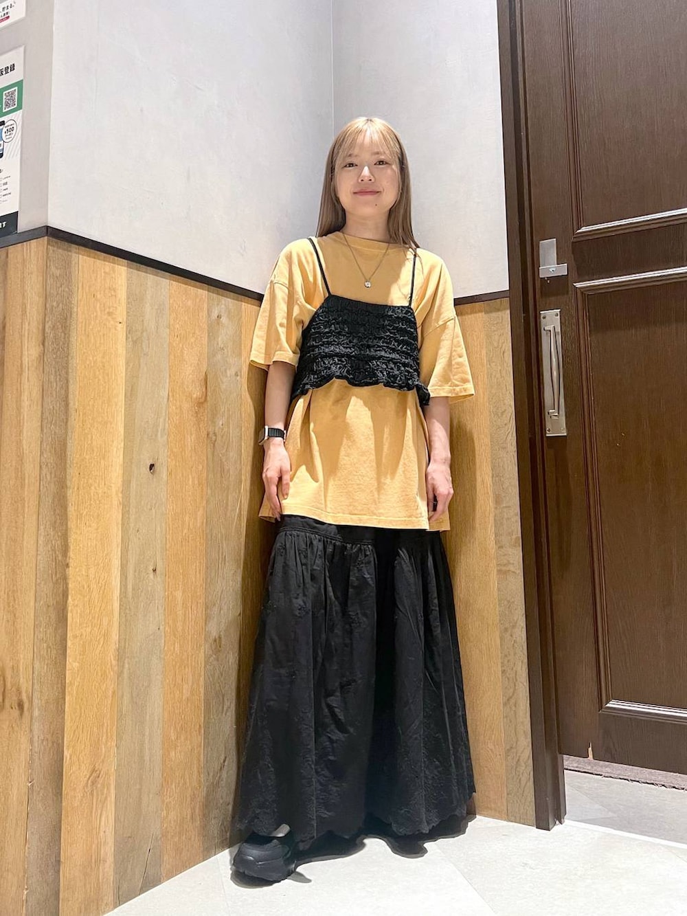 ブラック系のスニーカー、ブラック系のスカート、イエロー系のTシャツ/カットソーを着用したレディースの夏コーディネートの2枚目の写真