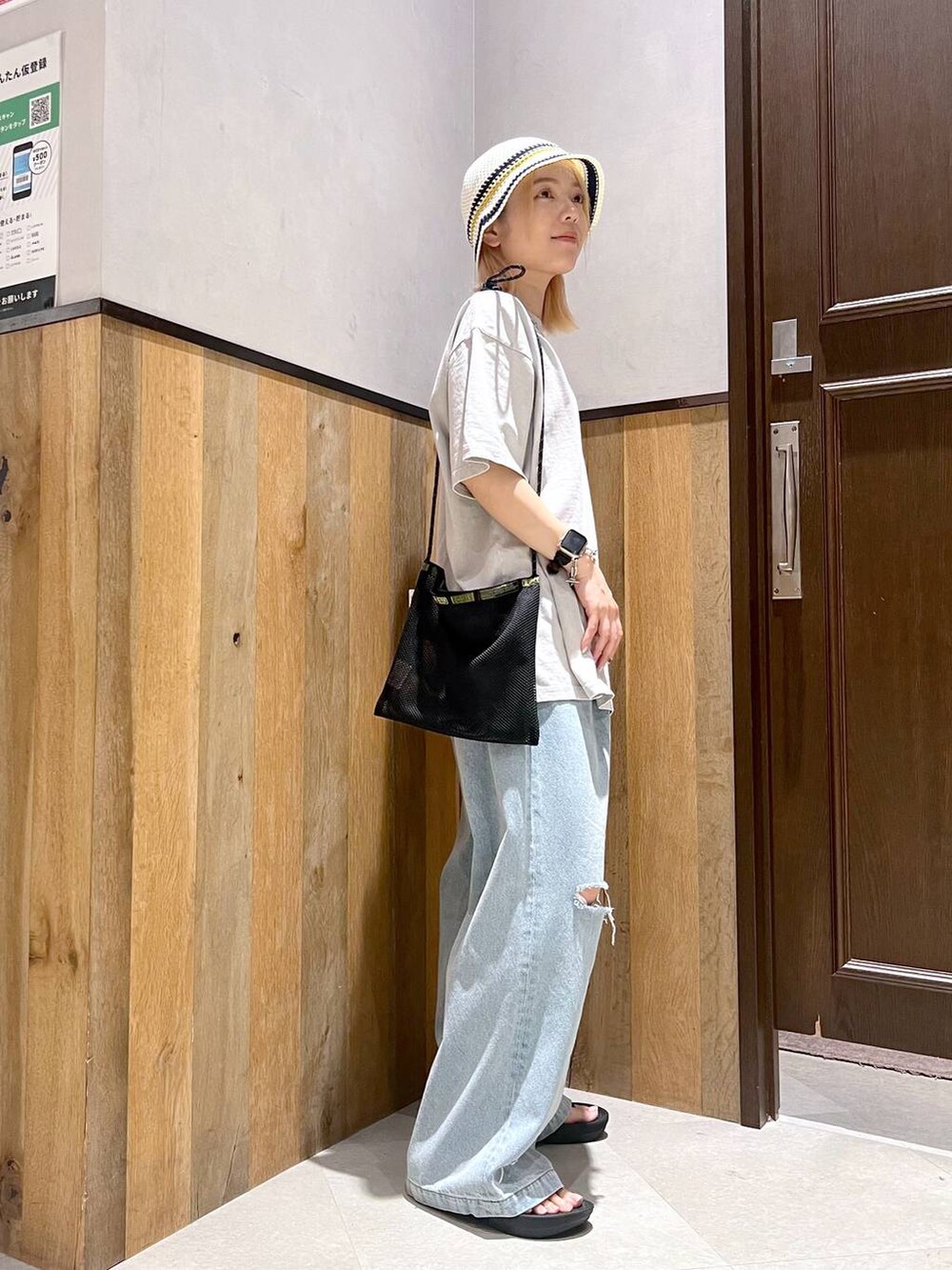 ブルー系のデニムパンツ、ブラック系のショルダーバッグ、ベージュ系のTシャツ/カットソーを着用したレディースの夏コーディネートの2枚目の写真