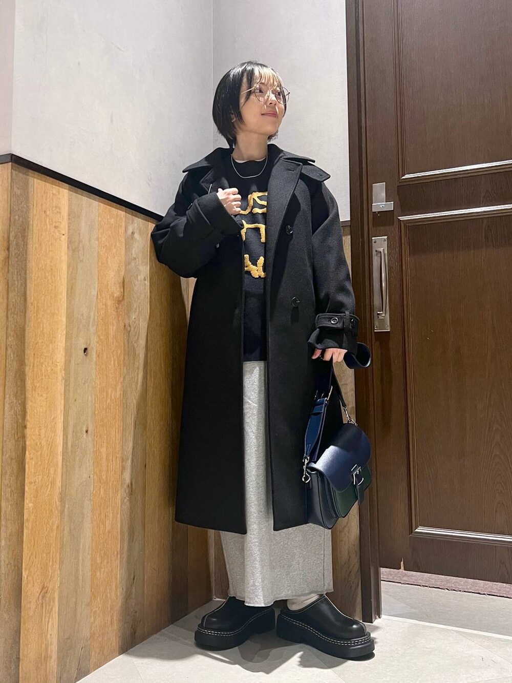 ブラック系のステンカラーコート、ブラック系のローファー、その他のスカートを着用したレディースの秋コーディネートの5枚目の写真