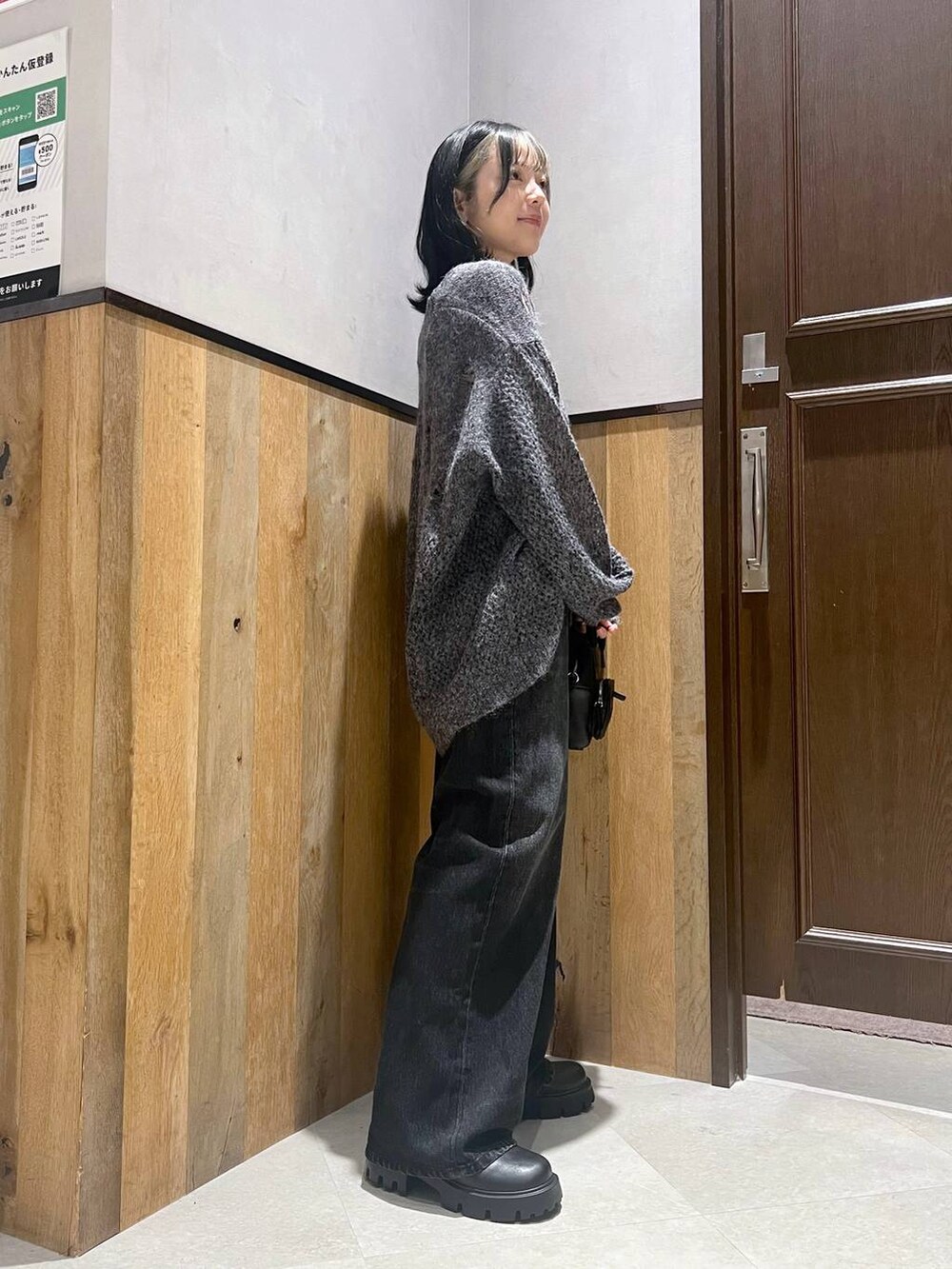 ブラック系のデニムパンツ、ブラック系のショルダーバッグ、ブラック系のブーツを着用したレディースの秋コーディネートの3枚目の写真