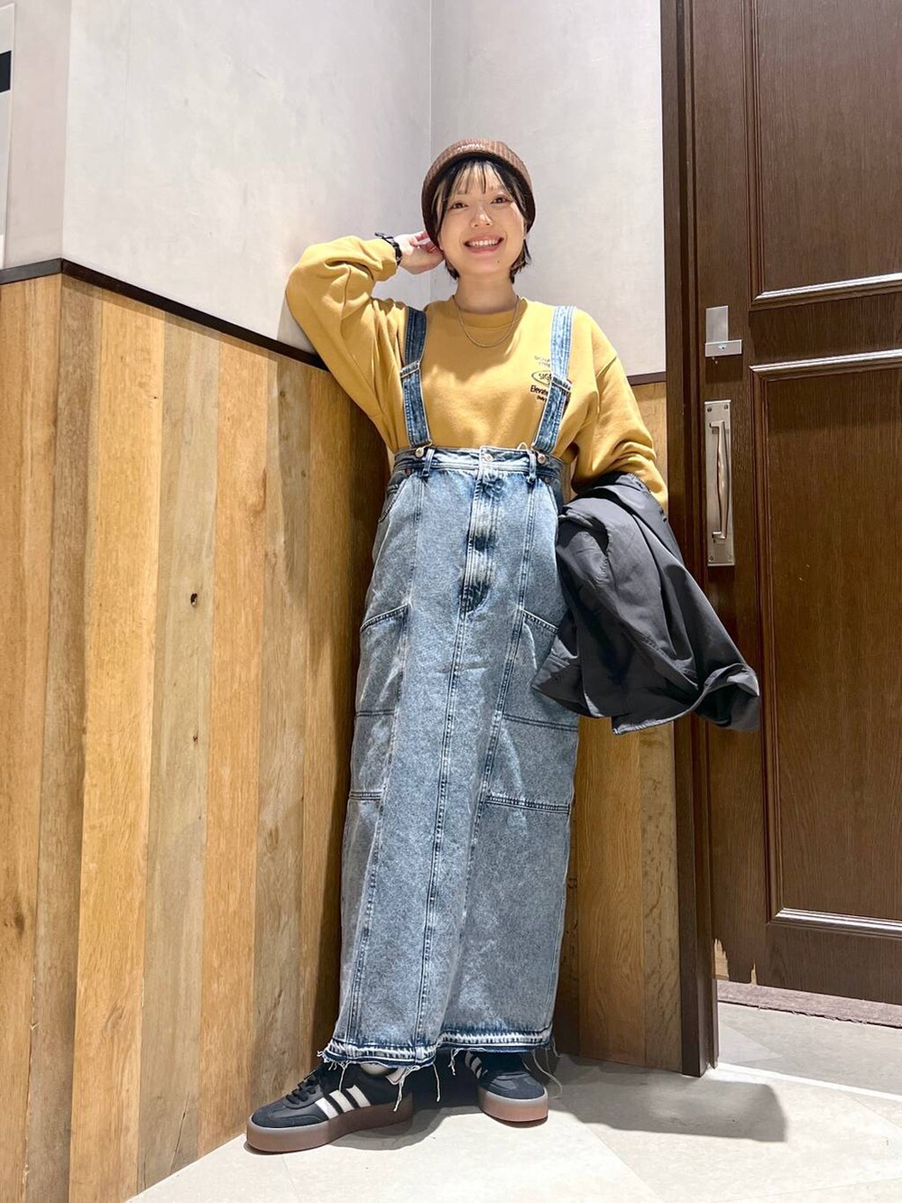 ブルー系のデニムスカート、ブラック系のブルゾン、イエロー系のスウェットを着用したレディースの秋コーディネートの3枚目の写真