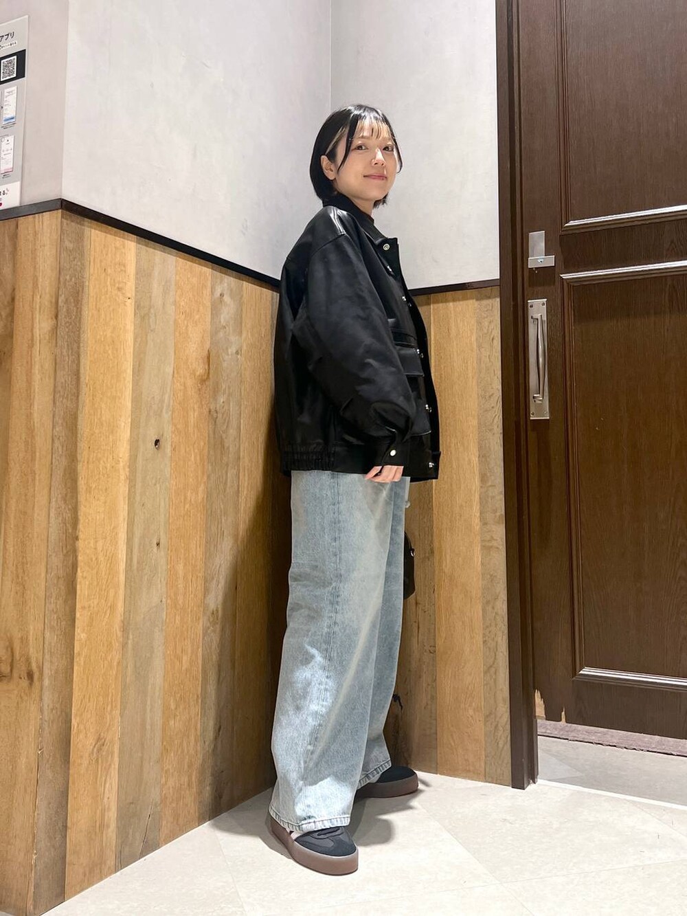 ブルー系のデニムパンツ、ブラック系のショルダーバッグ、ブラック系のブルゾンを着用したレディースの秋コーディネートの2枚目の写真