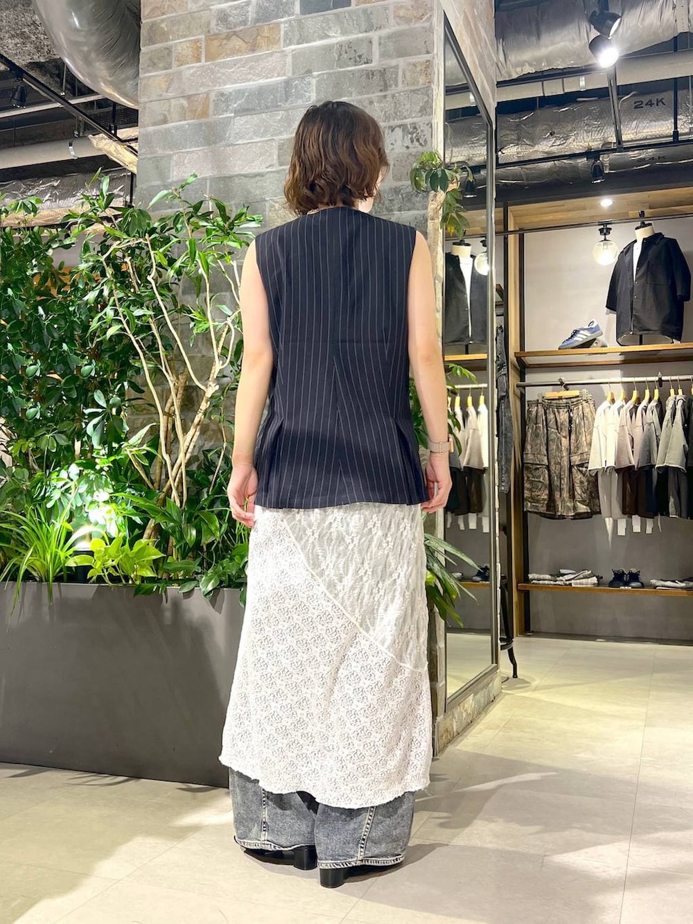 ホワイト系のタンクトップ、ブルー系のデニムパンツ、ブラック系のサンダルを着用したレディースの夏コーディネートの4枚目の写真