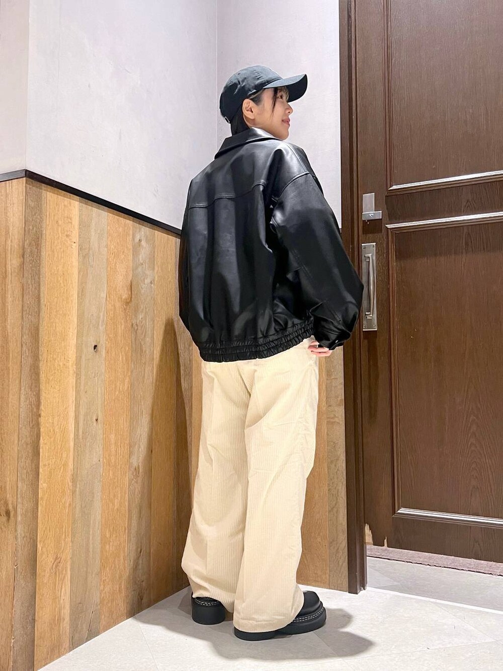 ホワイト系のスラックス、ブラック系のブルゾン、ブラック系のローファーを着用したレディースの秋コーディネートの3枚目の写真