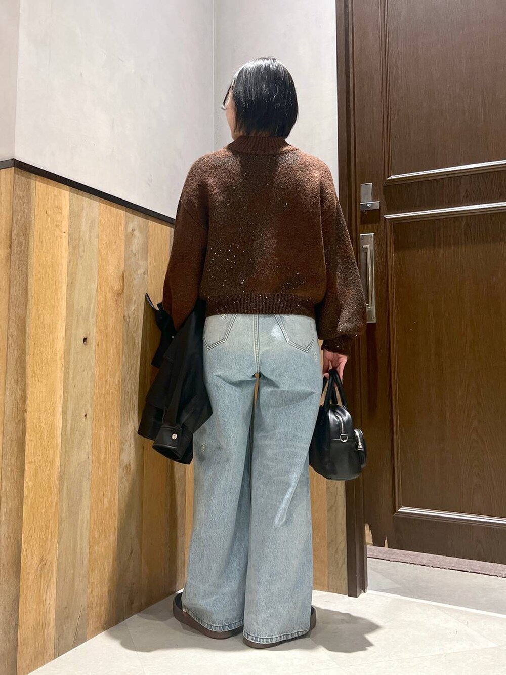 ブルー系のデニムパンツ、ブラック系のショルダーバッグ、ブラック系のブルゾンを着用したレディースの秋コーディネートの6枚目の写真