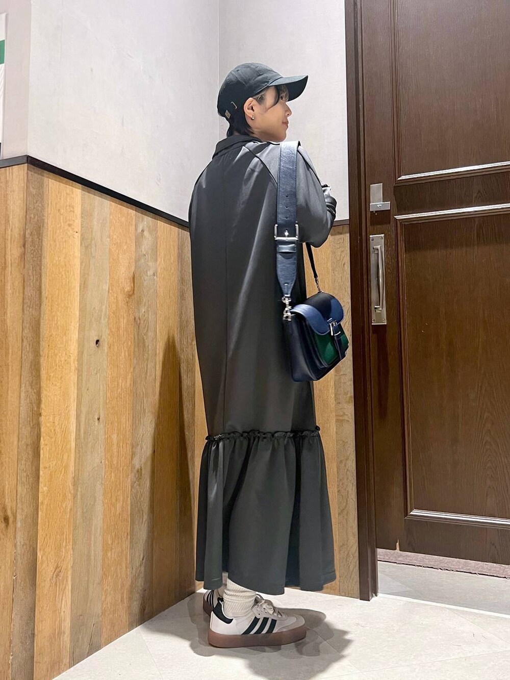 グレー系のワンピース、ホワイト系のスニーカー、ブルー系のショルダーバッグを着用したレディースの秋コーディネートの2枚目の写真