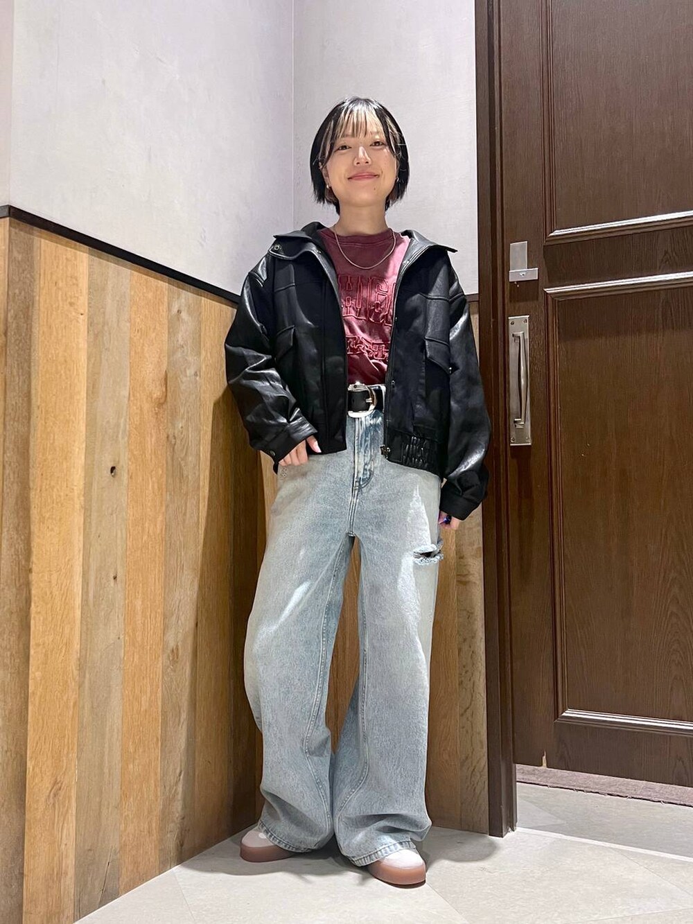 ブルー系のデニムパンツ、ブラック系のライダースジャケット、レッド系のTシャツ/カットソーを着用したレディースの秋コーディネートの2枚目の写真