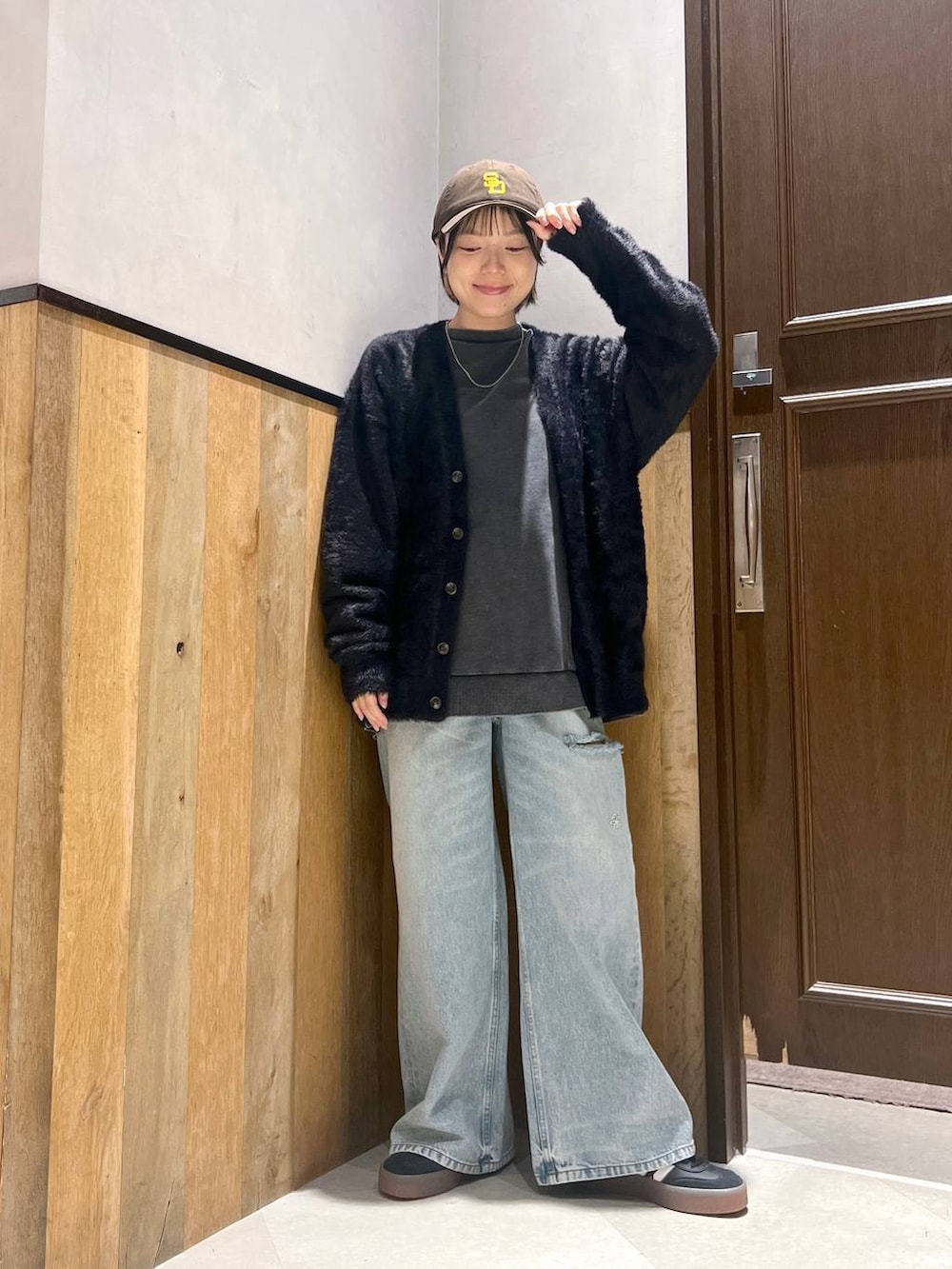 ブルー系のデニムパンツ、ブラック系のカーディガン/ボレロ、ブラック系のスウェットを着用したレディースの秋コーディネートの3枚目の写真