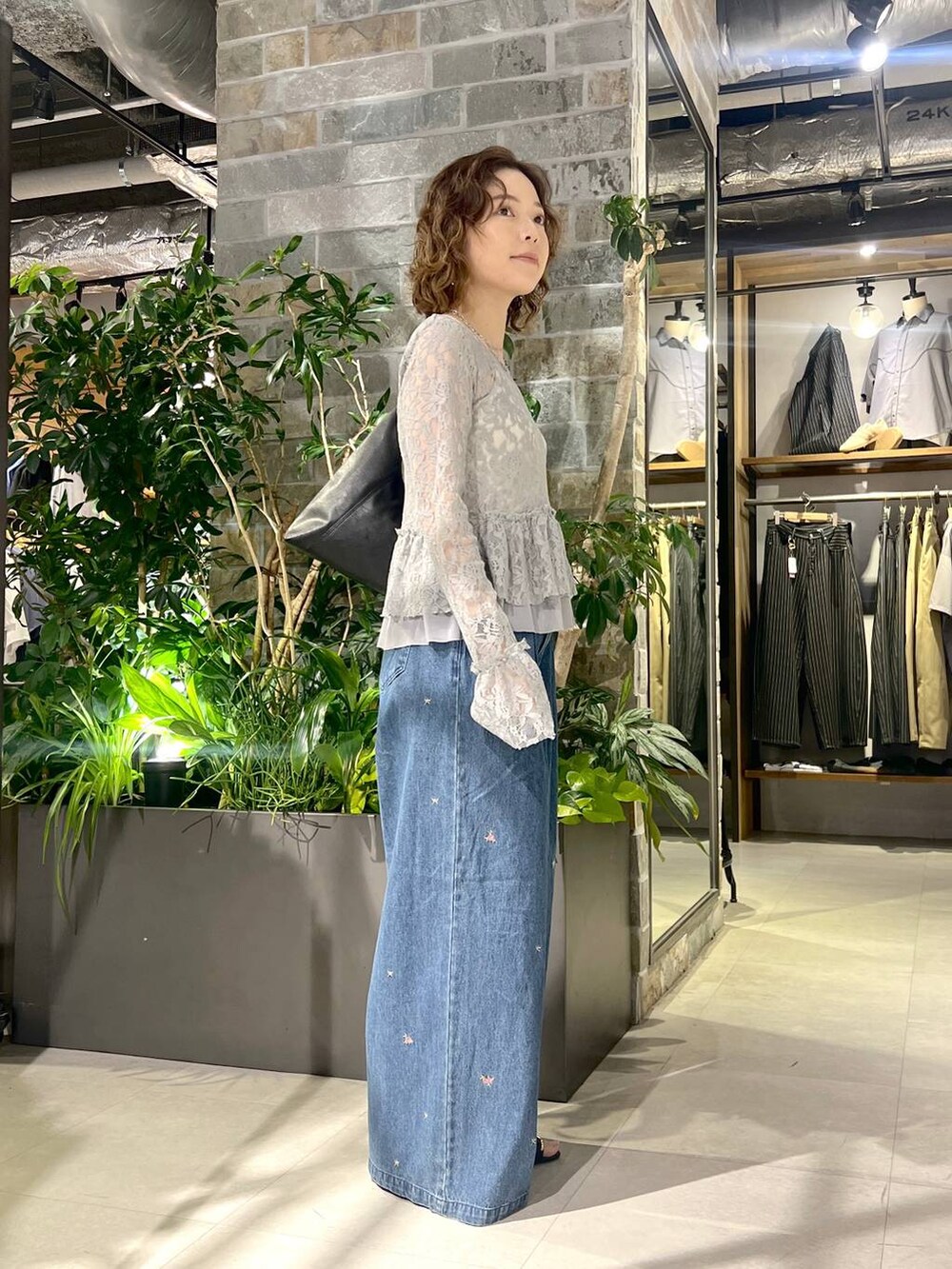 グレー系のTシャツ/カットソー、ブルー系のデニムパンツ、ブラック系のトートバッグを着用したレディースの夏コーディネートの3枚目の写真