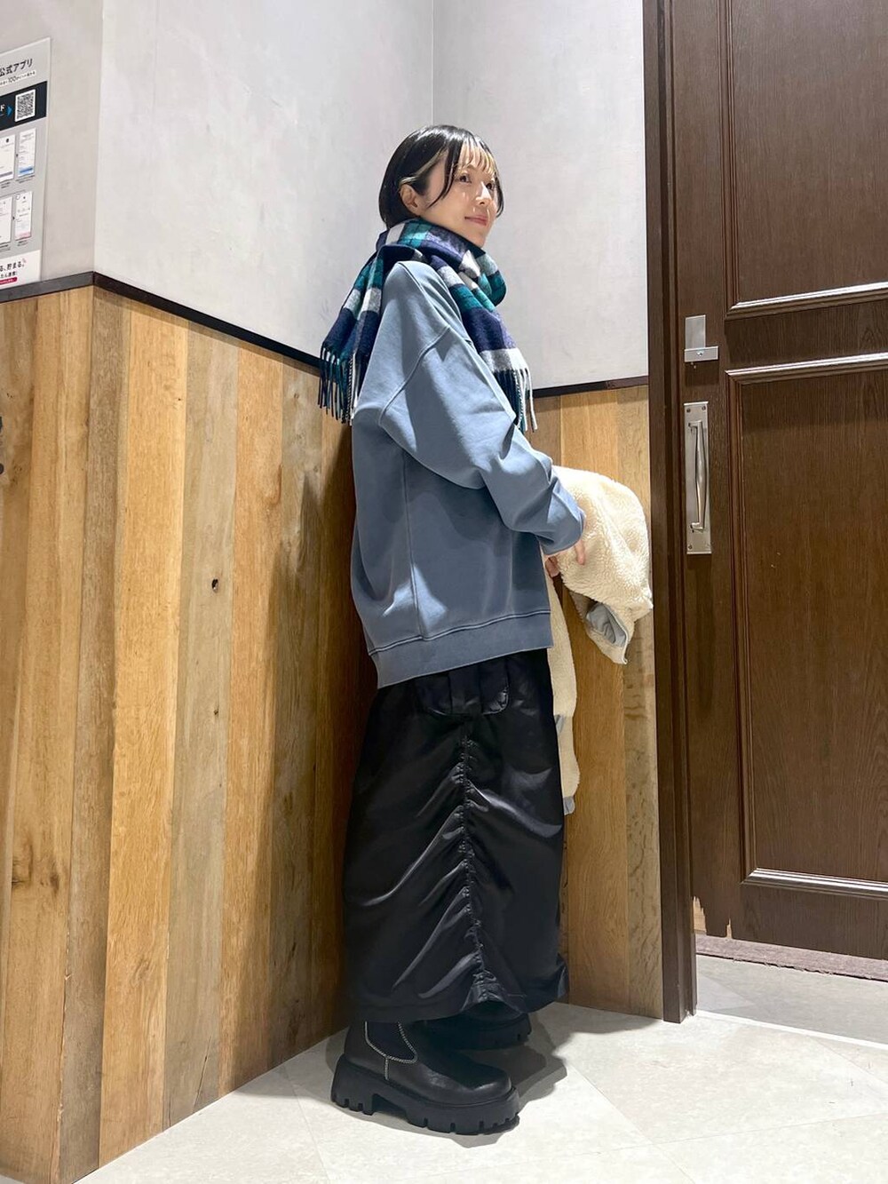 ホワイト系のブルゾン、ブラック系のブーツ、ブラック系のスカートを着用したレディースの秋コーディネートの2枚目の写真