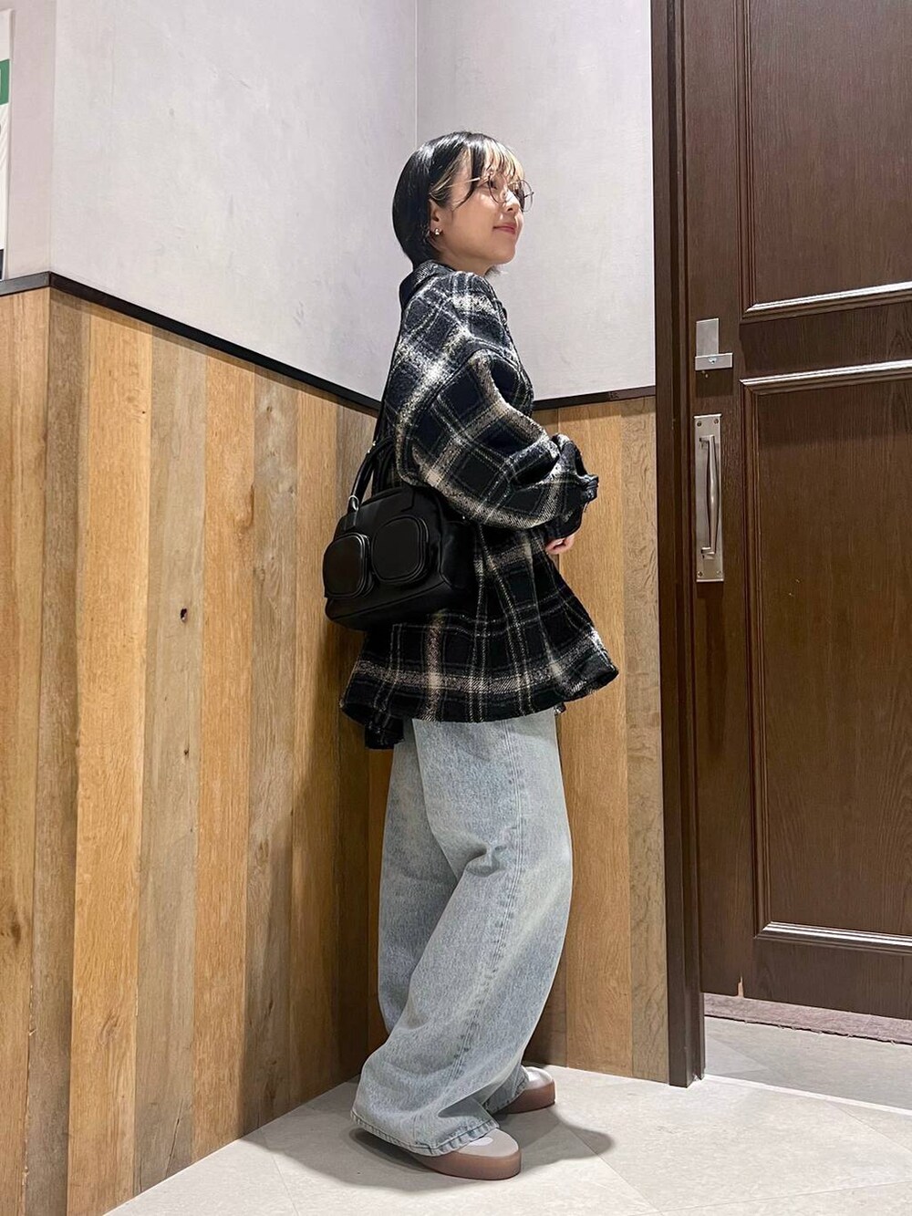 ブラック系のデニムパンツ、ブラック系のショルダーバッグ、ブラック系のシャツ/ブラウスを着用したレディースの秋コーディネートの2枚目の写真