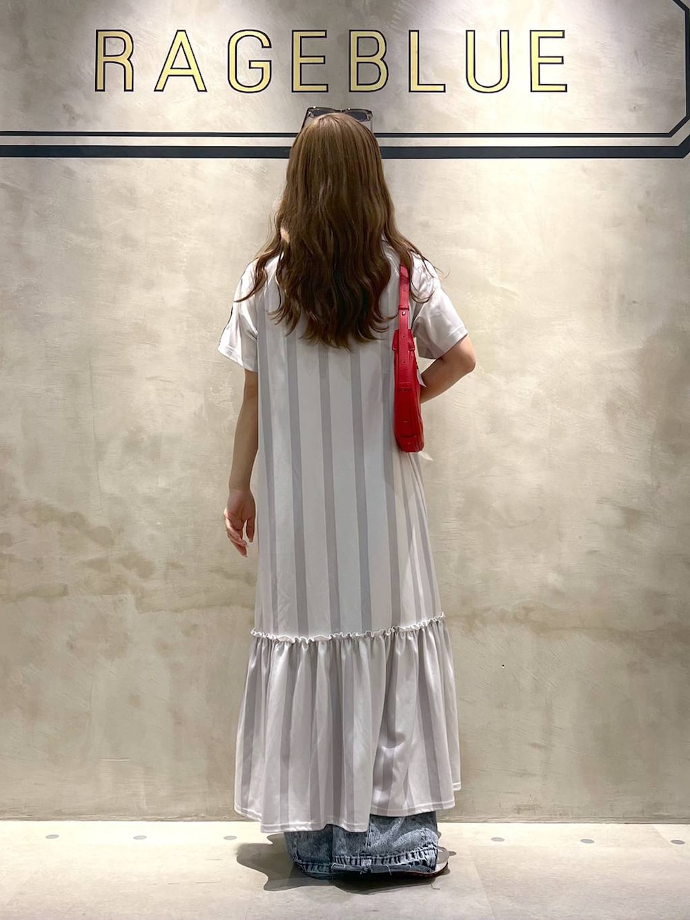 ホワイト系のワンピース、ブルー系のデニムパンツ、ホワイト系のスニーカーを着用したレディースの夏コーディネートの4枚目の写真