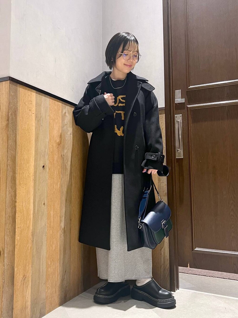 ブラック系のステンカラーコート、ブラック系のローファー、その他のスカートを着用したレディースの秋コーディネートの6枚目の写真