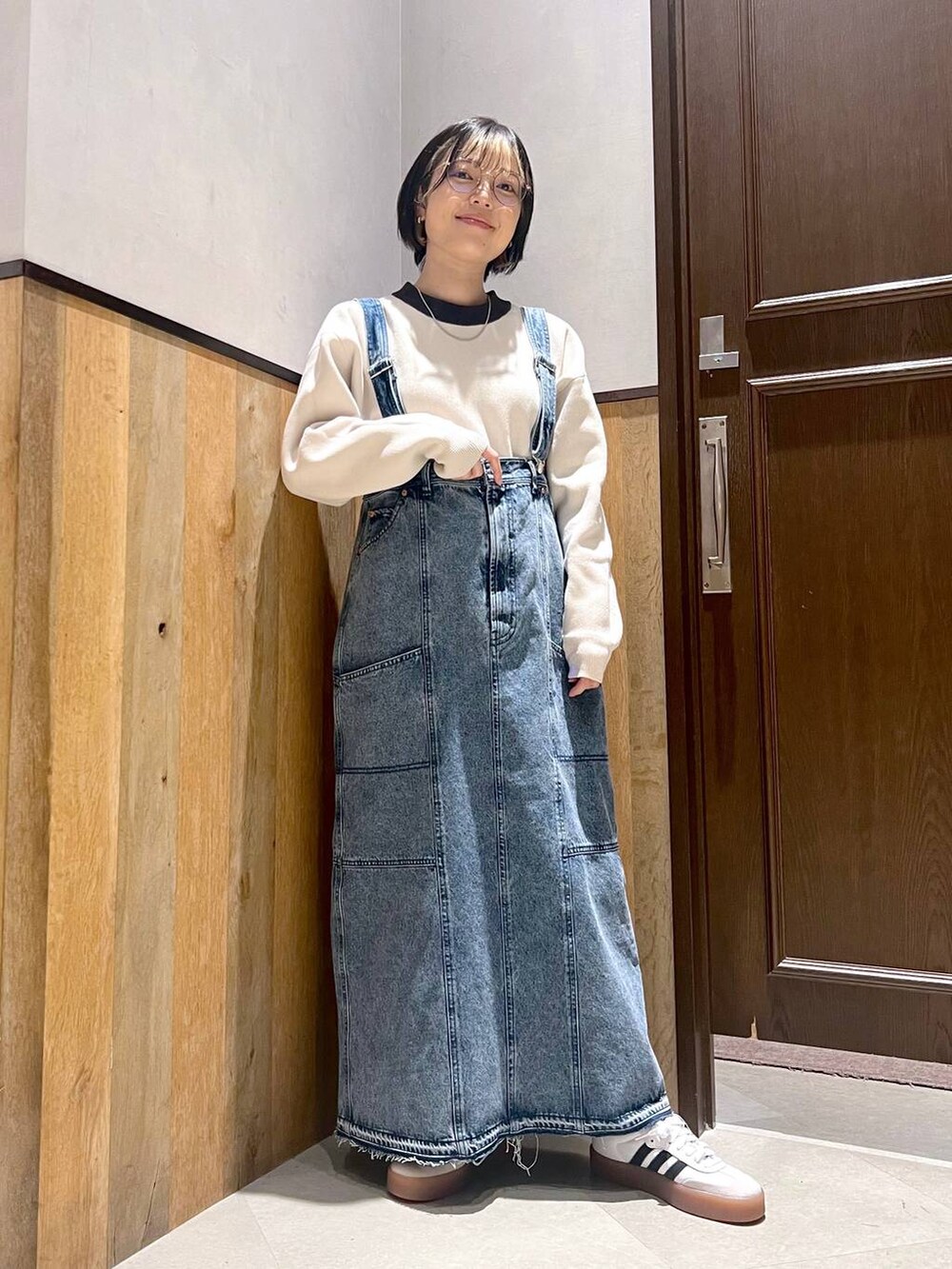 ブルー系のデニムスカート、ホワイト系のニット/セーター、ホワイト系のスニーカーを着用したレディースの秋コーディネートの2枚目の写真