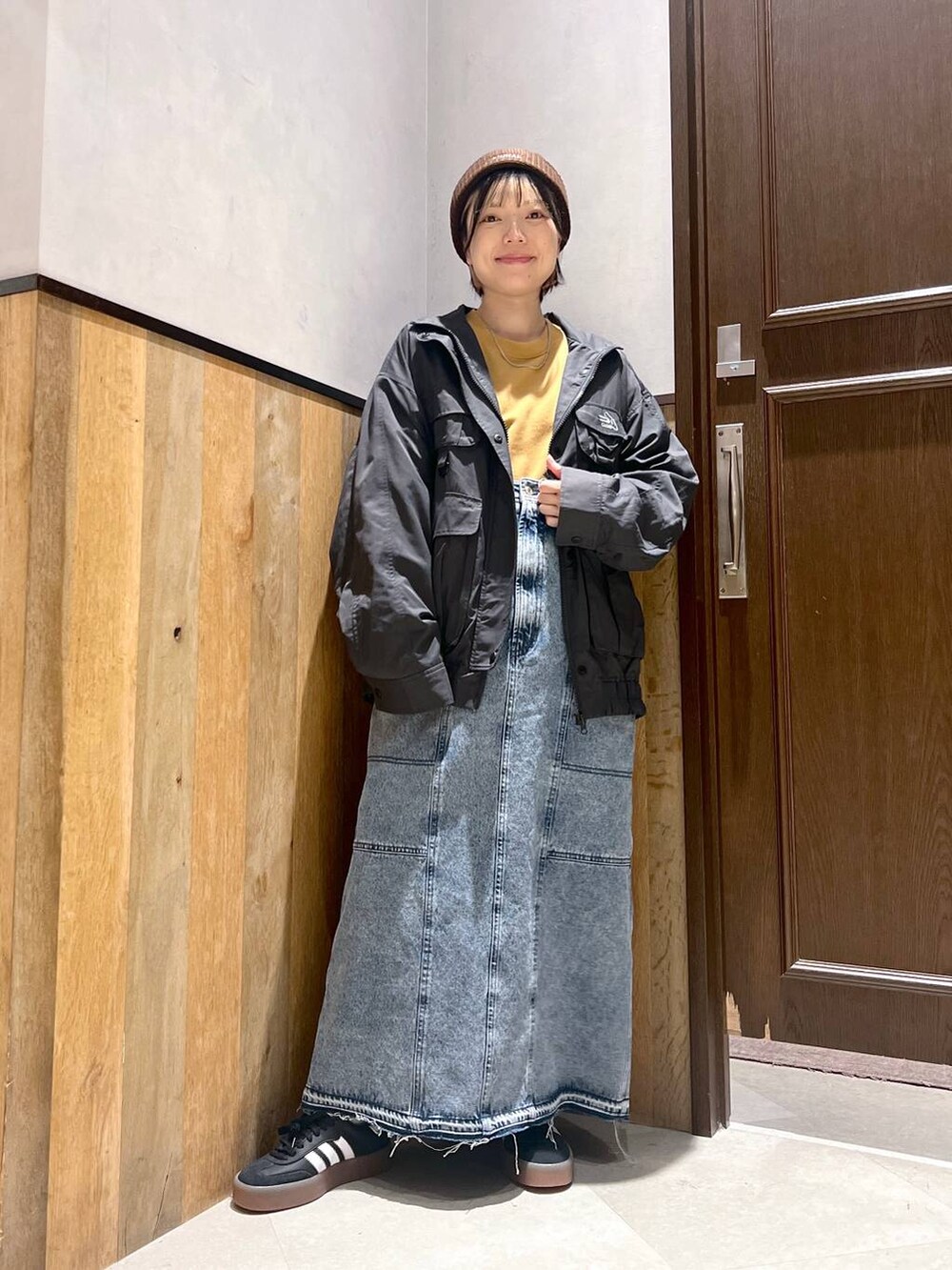 ブルー系のデニムスカート、ブラック系のブルゾン、イエロー系のスウェットを着用したレディースの秋コーディネートの4枚目の写真