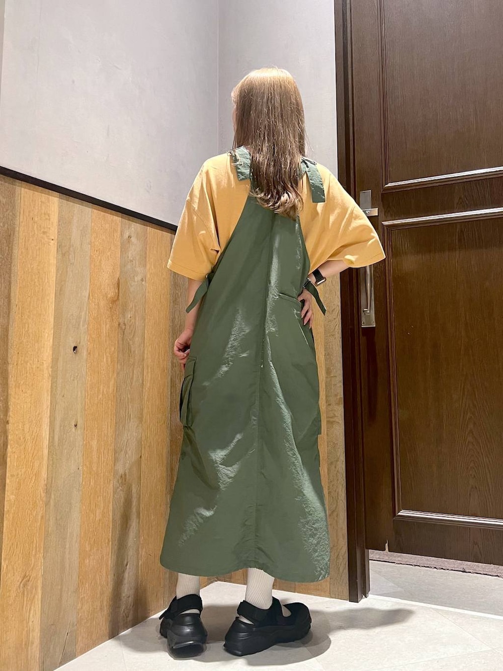 グリーン系のジャンパースカート、ブラック系のスニーカー、イエロー系のTシャツ/カットソーを着用したレディースの夏コーディネートの4枚目の写真