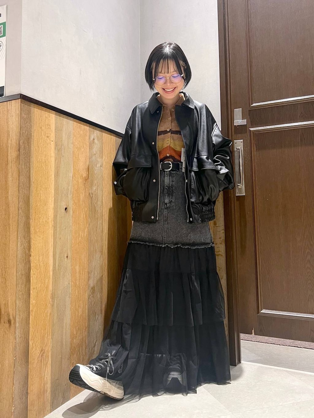 グレー系のブルゾン、ブラック系のデニムスカート、ブラック系のスニーカーを着用したレディースの秋コーディネートの5枚目の写真