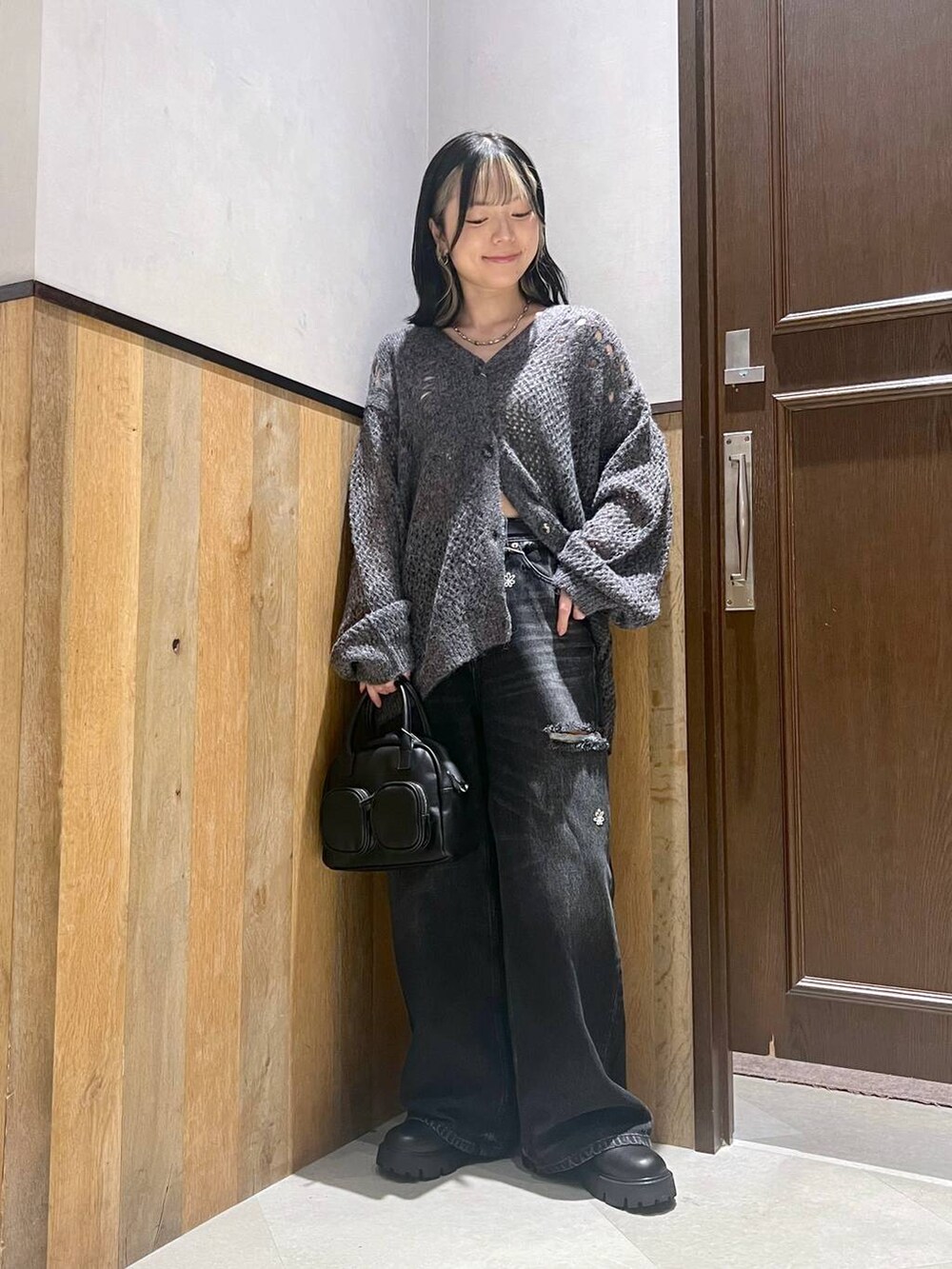 ブラック系のデニムパンツ、ブラック系のショルダーバッグ、ブラック系のブーツを着用したレディースの秋コーディネートの2枚目の写真