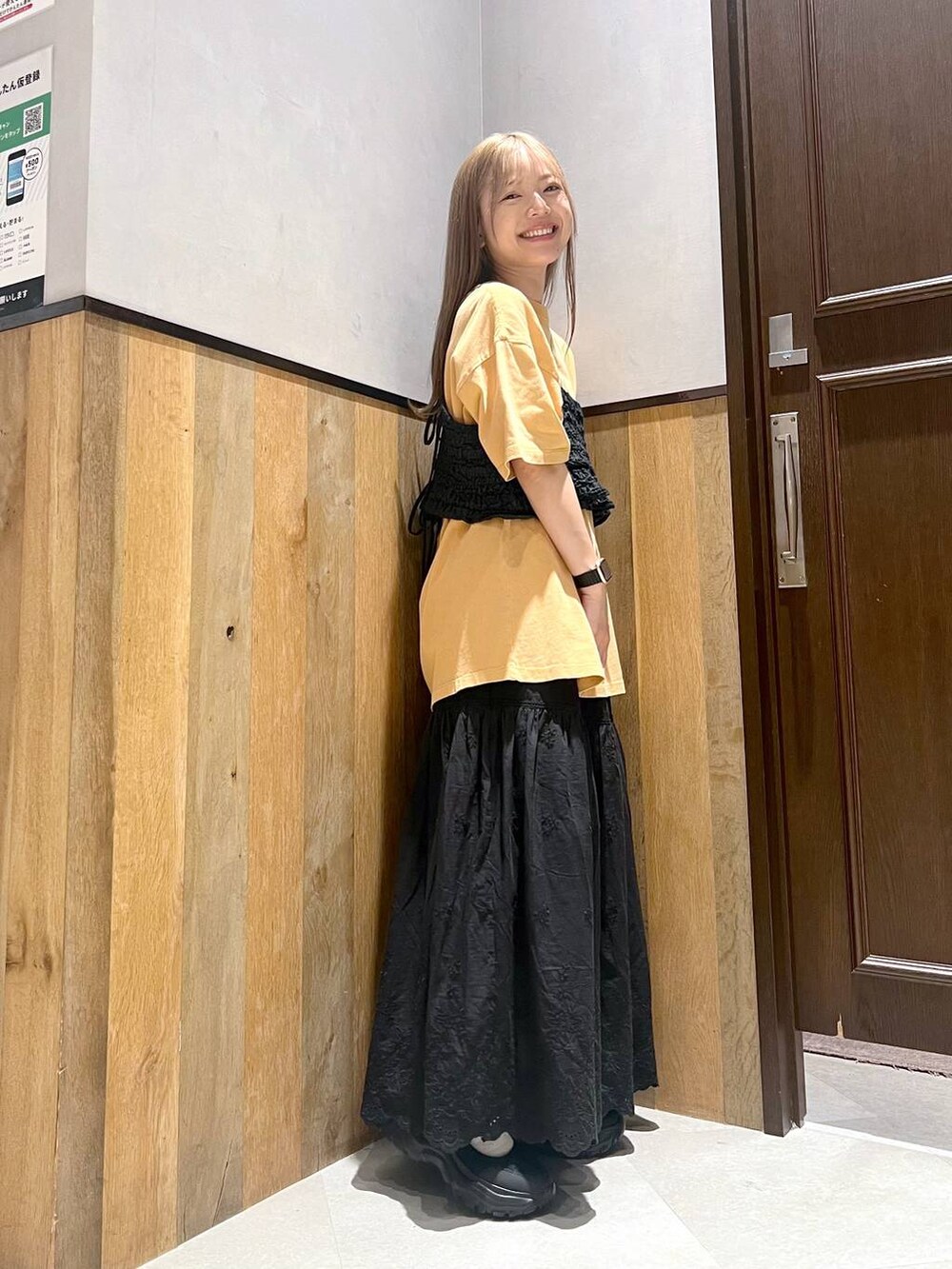 ブラック系のスニーカー、ブラック系のスカート、イエロー系のTシャツ/カットソーを着用したレディースの夏コーディネートの3枚目の写真