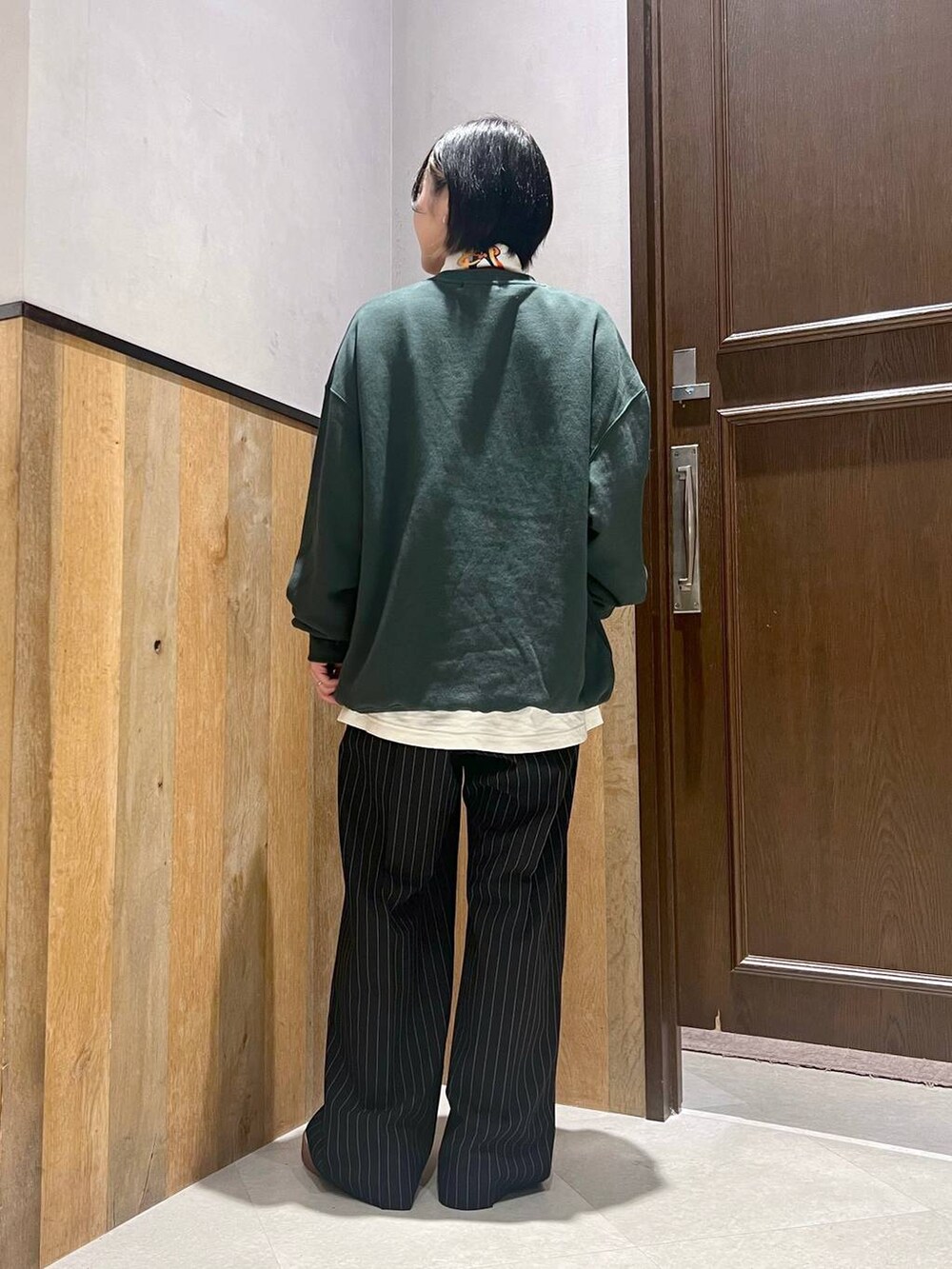 ブラック系のスラックス、ホワイト系のTシャツ/カットソー、グリーン系のスウェットを着用したレディースの秋コーディネートの3枚目の写真