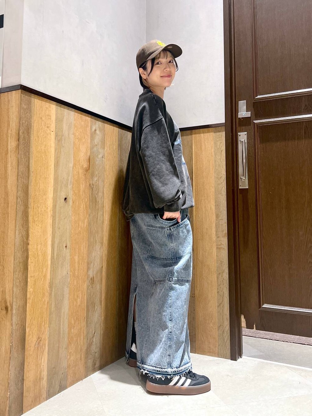 ブルー系のデニムスカート、ブラック系のスニーカー、グレー系のスウェットを着用したレディースの秋コーディネートの2枚目の写真