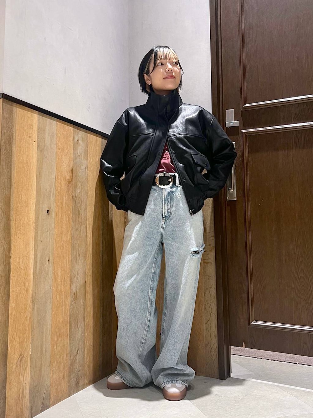 ブルー系のデニムパンツ、ブラック系のライダースジャケット、レッド系のTシャツ/カットソーを着用したレディースの秋コーディネートの6枚目の写真
