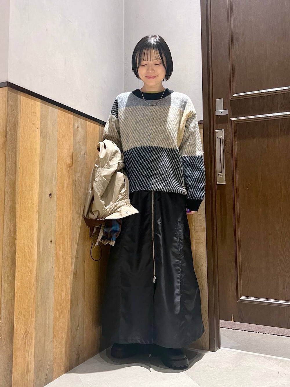 ブラック系のブーツ、ベージュ系のミリタリージャケット、ブラック系のジャンパースカートを着用したレディースの秋コーディネートの6枚目の写真