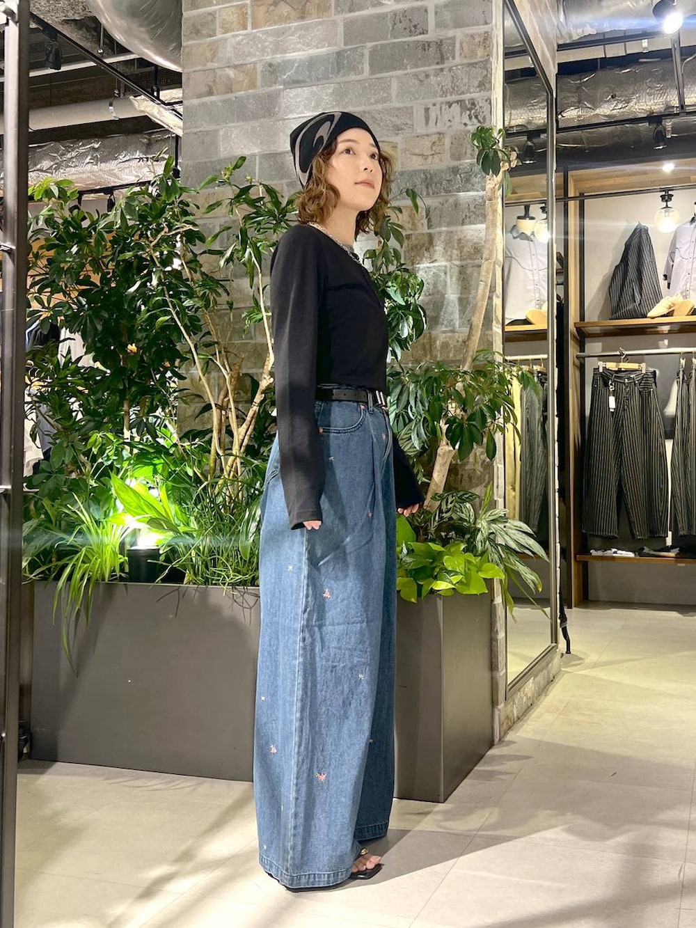 ブルー系のデニムパンツ、ブラック系のTシャツ/カットソー、ブラック系のサンダルを着用したレディースの夏コーディネートの2枚目の写真