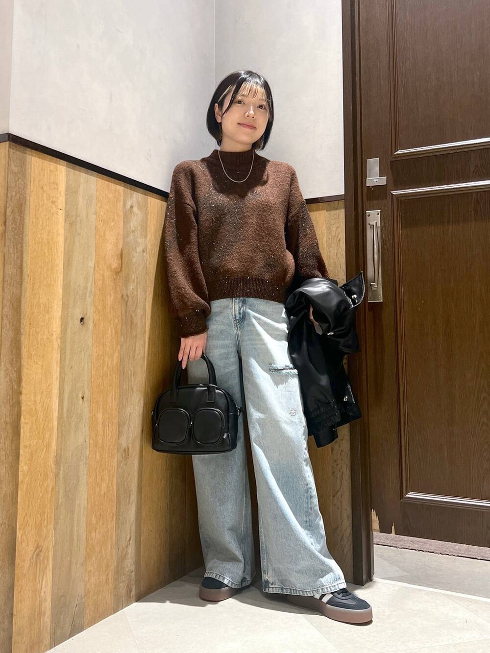 ブルー系のデニムパンツ、ブラック系のショルダーバッグ、ブラック系のブルゾンを着用したレディースの秋コーディネートの7枚目の写真