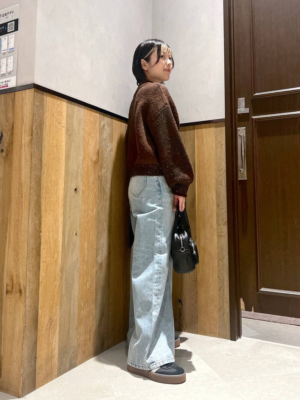 ブルー系のデニムパンツ、ブラック系のショルダーバッグ、ブラック系のブルゾンを着用したレディースの秋コーディネートの5枚目の写真