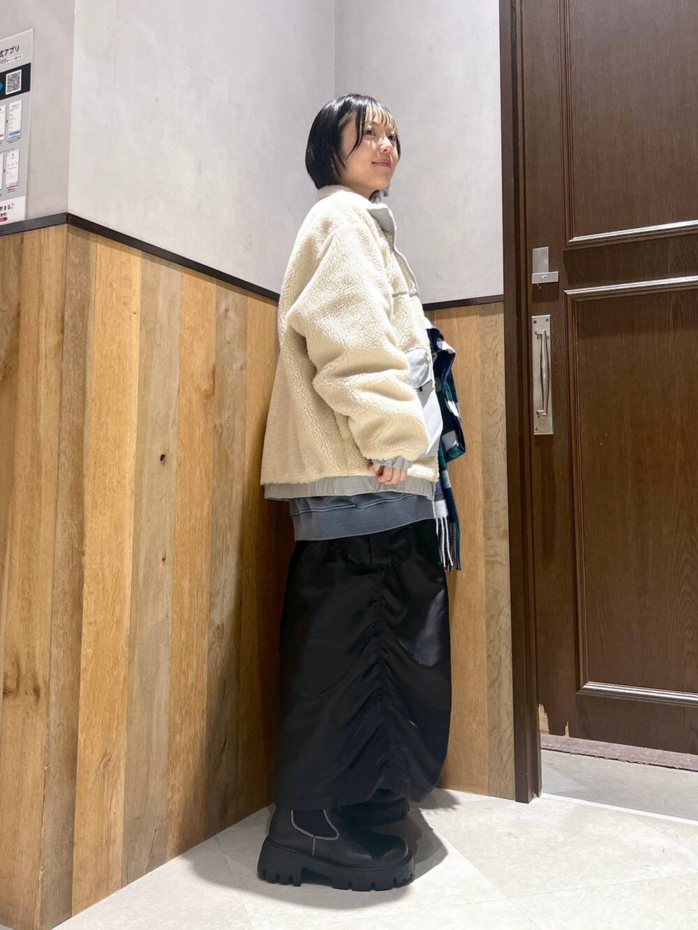 ホワイト系のブルゾン、ブラック系のブーツ、ブラック系のスカートを着用したレディースの秋コーディネートの5枚目の写真