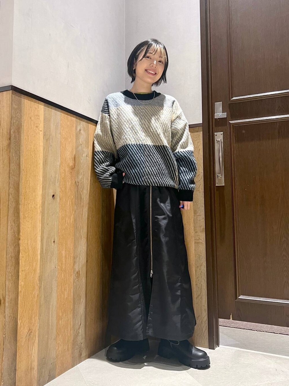 ブラック系のブーツ、ベージュ系のミリタリージャケット、ブラック系のジャンパースカートを着用したレディースの秋コーディネートの5枚目の写真