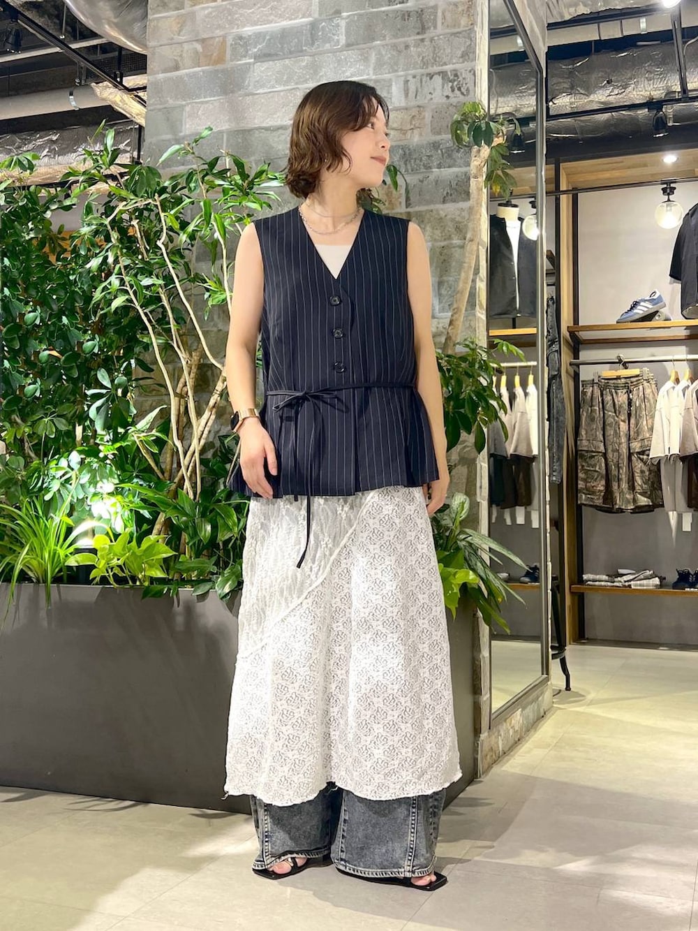ホワイト系のタンクトップ、ブルー系のデニムパンツ、ブラック系のサンダルを着用したレディースの夏コーディネートの2枚目の写真