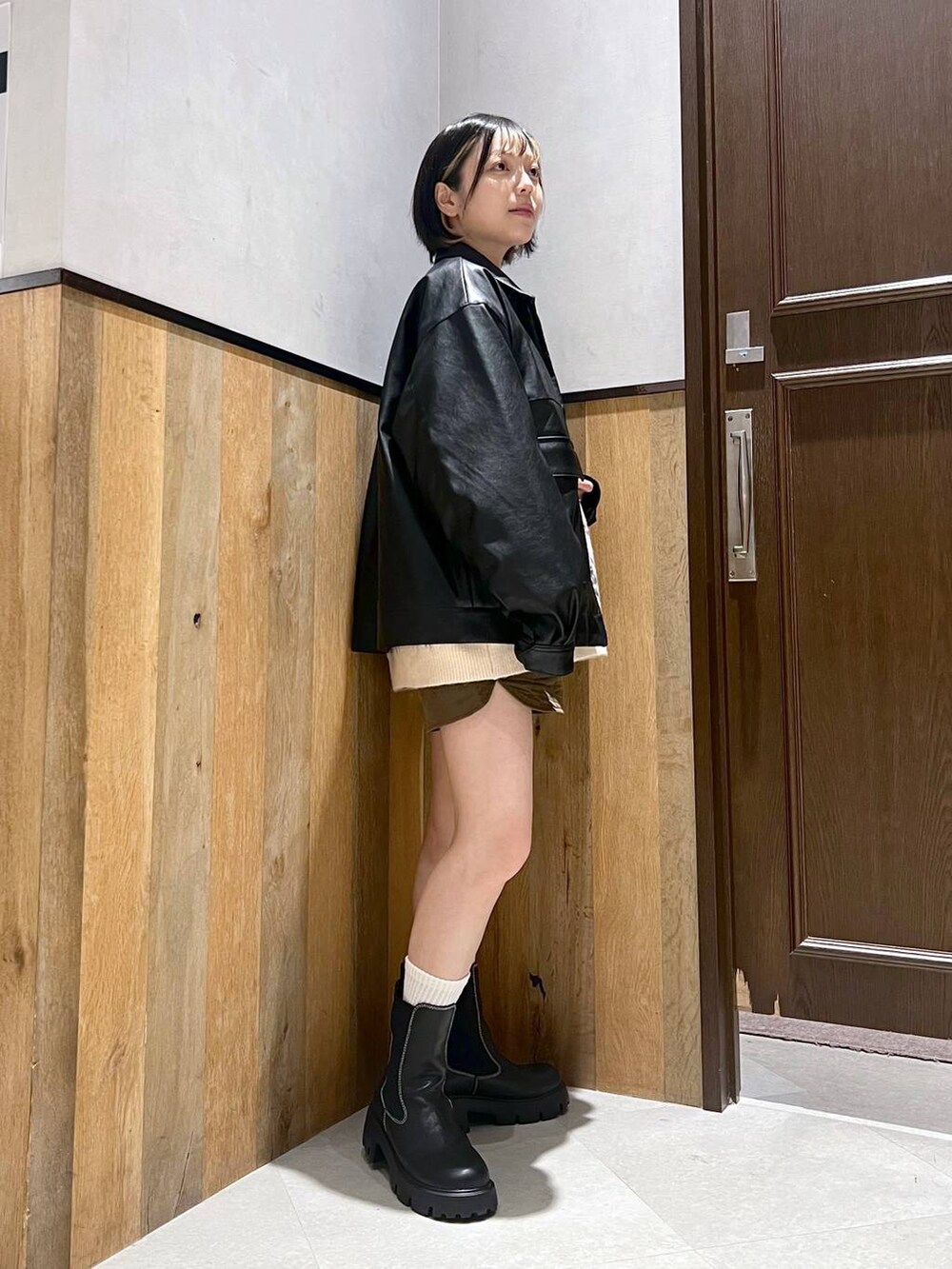 ブラック系のブーツ、ホワイト系のニット/セーター、ブラック系のブルゾンを着用したレディースの秋コーディネートの3枚目の写真