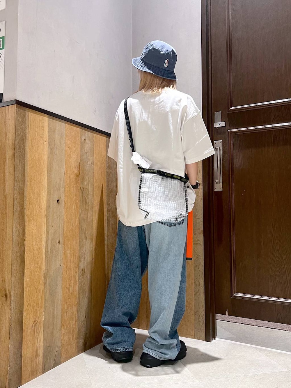 ブラック系のスニーカー、ブルー系のデニムパンツ、ブラック系のショルダーバッグを着用したレディースの秋コーディネートの3枚目の写真