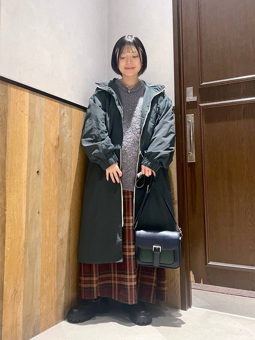 グリーン系のニット/セーター、ブラック系のブーツ、ブルー系のショルダーバッグを着用したレディースの秋コーディネートの4枚目の写真