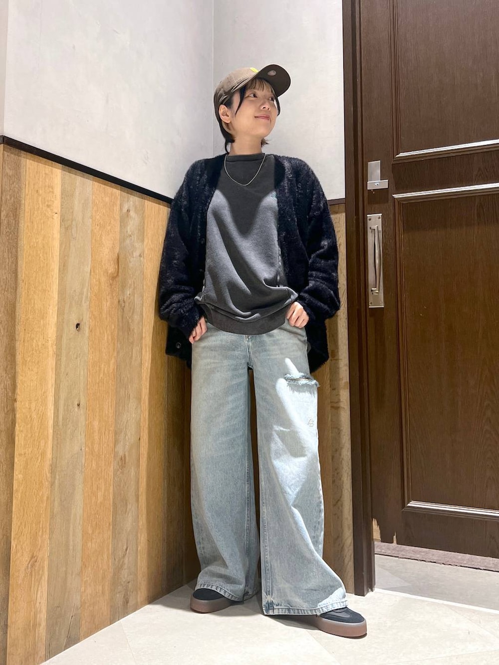 ブルー系のデニムパンツ、ブラック系のカーディガン/ボレロ、ブラック系のスウェットを着用したレディースの秋コーディネートの2枚目の写真