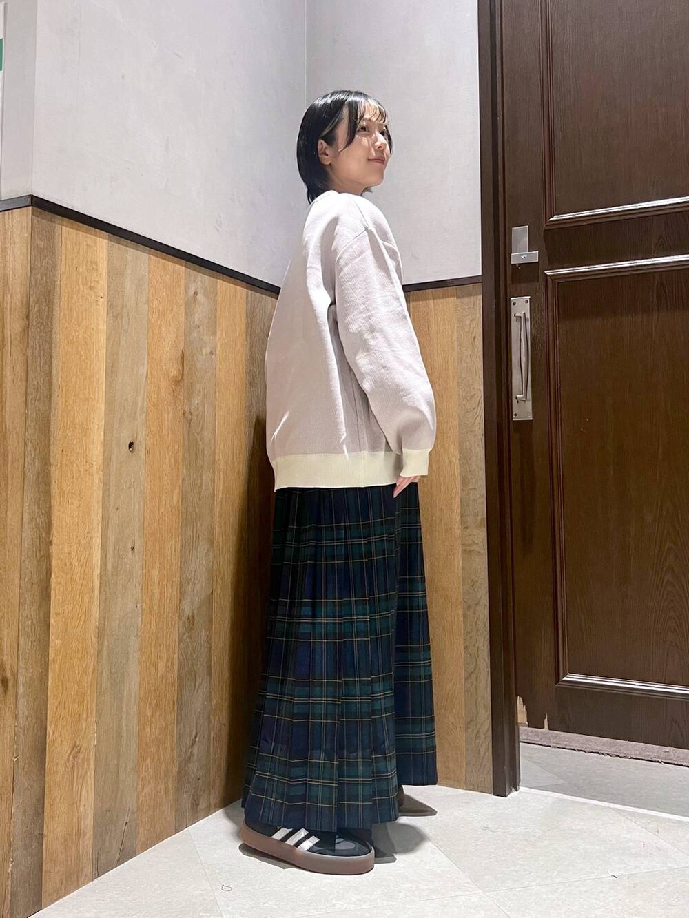 ホワイト系のニット/セーター、グリーン系のスカート、ブラック系のスニーカーを着用したレディースの秋コーディネートの3枚目の写真